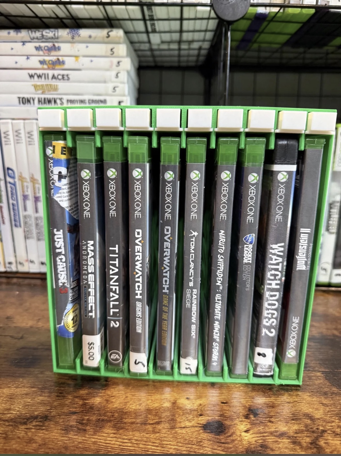 Green push-button game storage rack holding Xbox One cases